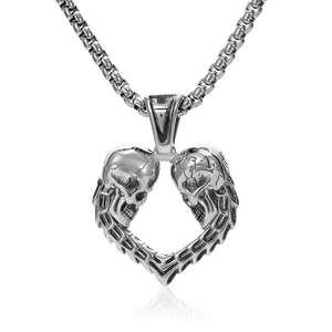 Détail d'un pendentif cœur avec deux crânes sur chaîne argentée avec effet miroir