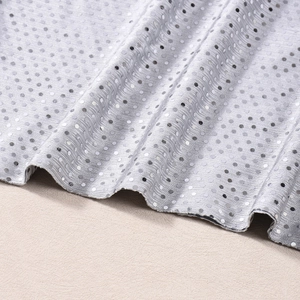 Gros plan du tissu à paillettes argentées montrant la texture sur fond beige clair
