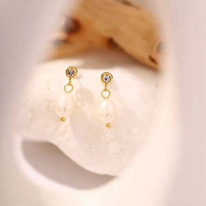 Primer plano de pendientes vintage de oro con perlas de agua dulce y piedras de circón