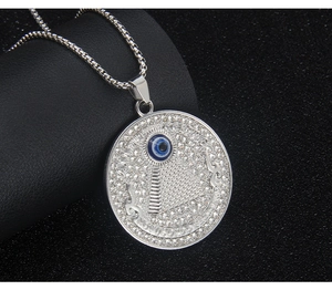 Macro shot of silver pyramid evil eye pendant with crystal pavé and Latin engraving