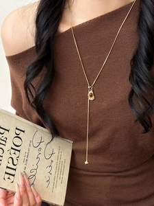 Detail view of Y-shaped gold necklace with brown heart pendant and long metal tassel