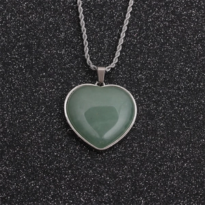 Green heart jade pendant necklace with silver twisted chain on black sparkly background