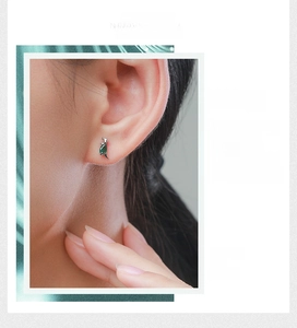 Detail of s925 silver dinosaur stud earring featuring a pear-shaped green crystal gem