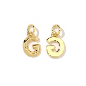 Macro detail of 18K gold plated letter G pendant charms with a shiny polished finish