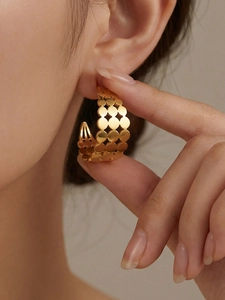 Détail de boucles d'oreilles dorées creuses en C avec texture géométrique sur le mannequin