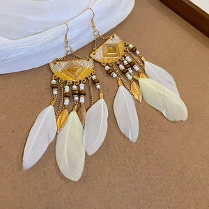 Detail of bohemian drop earrings with golden metal, white feathers and colorful beads