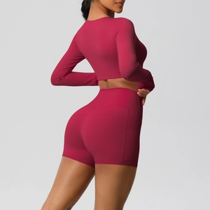 Detail van de yoga shorts met hoge taille, zijzak en crop top met lange mouwen in rood