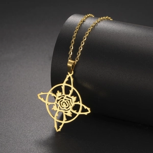 Détail d'un collier en acier doré avec pendentif étoile ajourée et motif rose sur socle