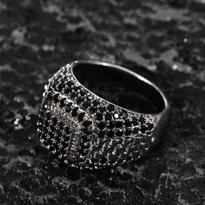 Macro shot of men's wide silver ring with micro-paved black zircons on rock background
