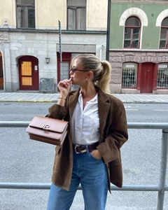 Detail of dark brown suede blazer paired with an embroidery shirt and leather crossbody bag
