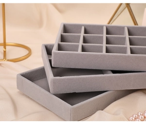 Close-up of grey velvet jewelry trays with multiple compartments for rings and earrings