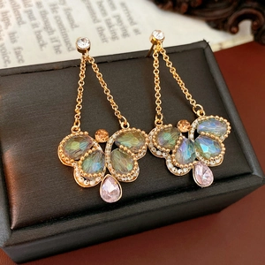 Detailed macro view of vintage butterfly drop earrings with colorful gems and tassels