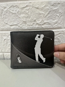 Detailed view of a black leather wallet with white golfer silhouette and metallic golf ball décor