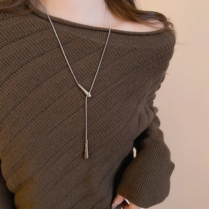 Detail of silver teardrop pendant on snake chain necklace worn over a brown knit sweater