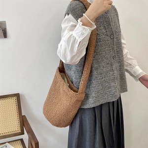Close-up of brown plush teddy tote bag with wide shoulder strap on a female model