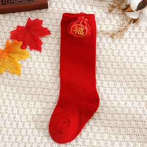Detail of red baby festive long socks featuring a Fu bag accessory and soft cotton knit