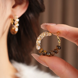 Detail view of C-shaped hoop earrings with tiger eye beads and faceted crystals