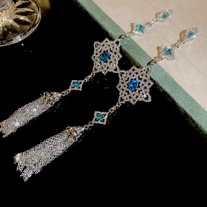 Detailed shot of elegant silver tassel earrings with blue gemstones and sparkling crystals