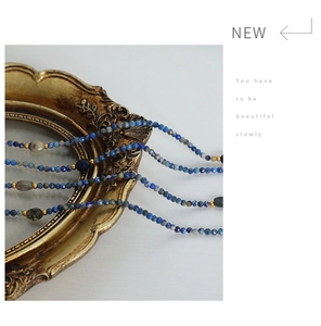 Detail of faceted blue natural stone beads with gold spacers on vintage frame