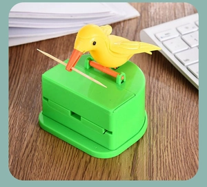 Close-up of a yellow bird automatic toothpick holder picking up a single toothpick