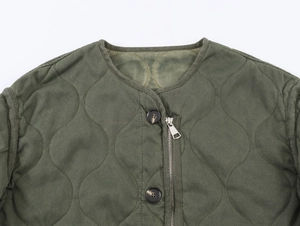 Detail view of army green quilted jacket with round neck, zipper and button closure