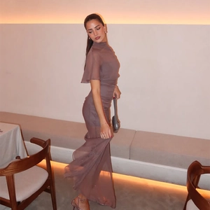 Detail of elegant brown sleeveless chiffon maxi dress with ruffle sleeves and side slit
