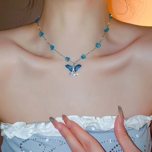 Primer plano de un collar de mariposa con piedras azules y perlas blancas en una modelo