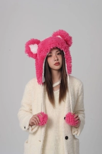 Detailed close-up of fluffy strawberry pink plush bucket hat with large pom-pom earflaps