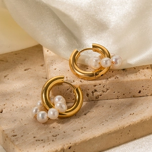 Detail of 18K gold hoop earrings with irregular white pearls on beige silk and stone