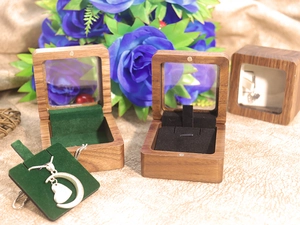 Detail of walnut wood jewelry box with clear window and forest green velvet lining