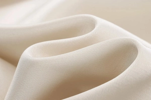 Detail of elegant champagne satin dress fabric showing smooth silk texture and soft folds