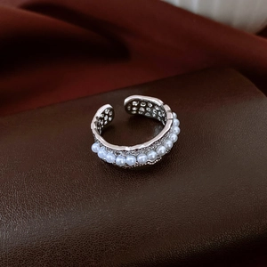Detailed macro shot of adjustable silver-tone pearl ring with hollow metal band