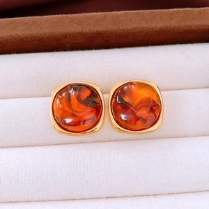 Macro view of amber resin earrings with golden metal frames in a velvet box
