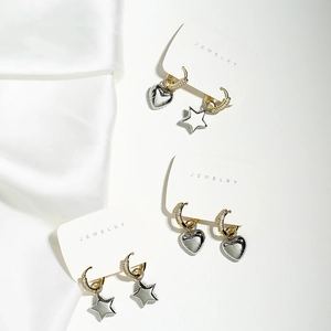 Detailed display of three pairs of gold hoops with silver heart and star charms