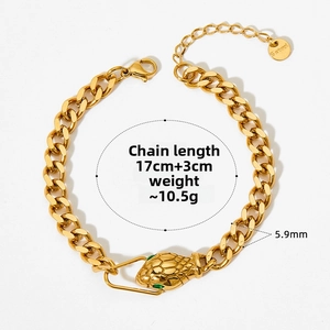 Detail of gold snake head clasp on Cuban chain bracelet with green stone eyes and logo tag