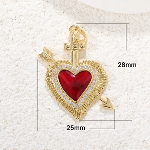 Close-up of a heart pendant with a sword and arrow design featuring a red gemstone
