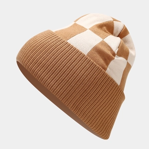 Détail d'un bonnet d'hiver en tricot à damier marron et blanc avec bord côtelé