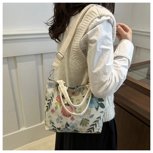 Ethnic canvas tote bag featuring floral embroidery shown on model in indoor setting