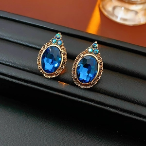 Détail de boucles d'oreilles vintage style palais avec pierre bleue ovale et dorure