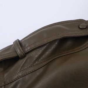 Détail de veste en similicuir vert olive avec coutures et bouton recouvert de cuir