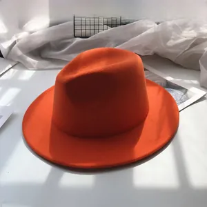 Close-up of bright orange wool fedora hat with wide brim and classic indented crown detail