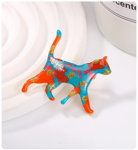 Detail of colorful enamel cat brooch with blue and orange patches and gold glitter finish