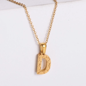 Macro view of 18K gold plated letter D necklace pendant with detailed stone texture finish