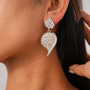 Detail view of a silver textured heart earring with metallic finish on a female model