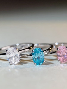 Macro shot of oval cut white, blue, and pink sparkling gemstones in silver claw settings