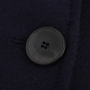 Detailed macro shot of a black four-hole resin button on navy blue wool fabric texture