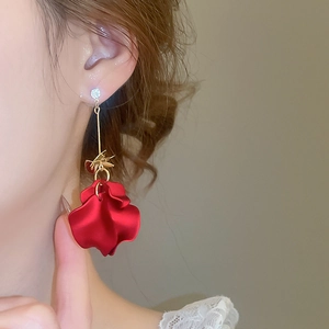 Detail of elegant long red flower petal earrings with zircon studs on a female model