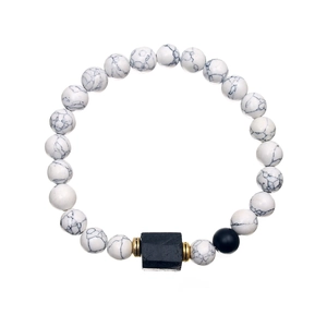 Macro shot of white turquoise beads with black rectangular accent and golden spacers