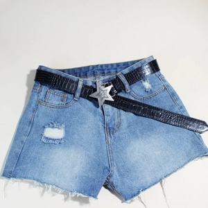 Detail der Vintage-Sternschnalle am schwarzen Kunstleder-Gürtel auf hellblauen Jeans