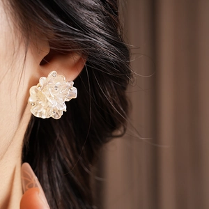 Gros plan d'une boucle d'oreille fleur en résine blanche avec strass sur un mannequin